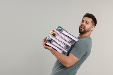 Photo of Stressful man with folders on light gray background, space for text