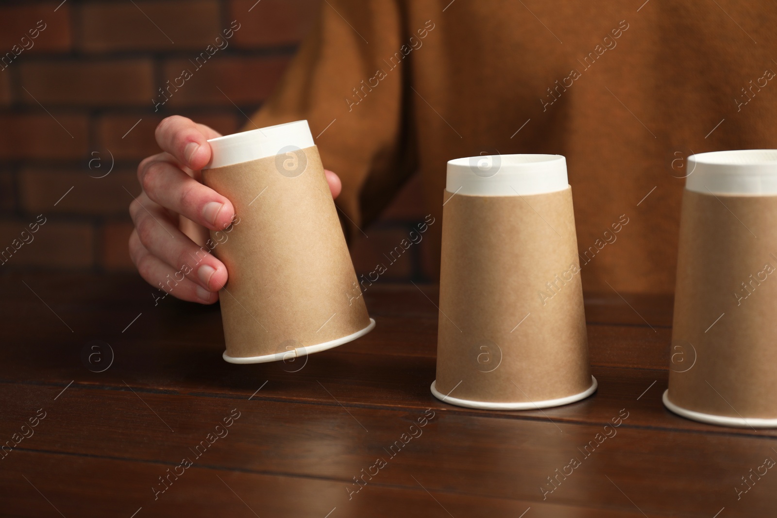 Photo of Man playing shell game at wooden table, closeup