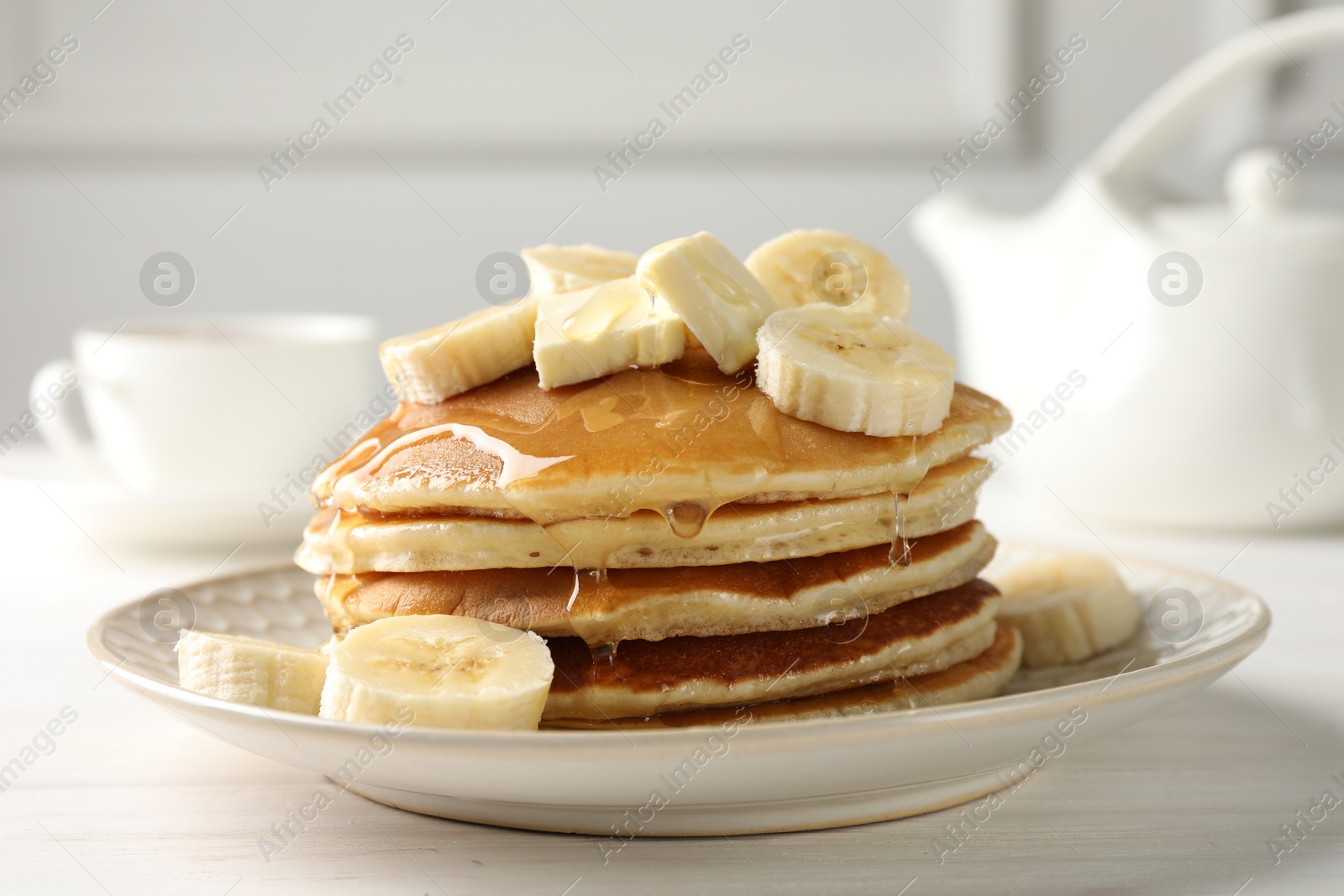 Photo of Delicious pancakes with bananas, honey and butter on white wooden table, closeup