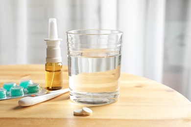 Photo of Glass with water and different cold remedies on table