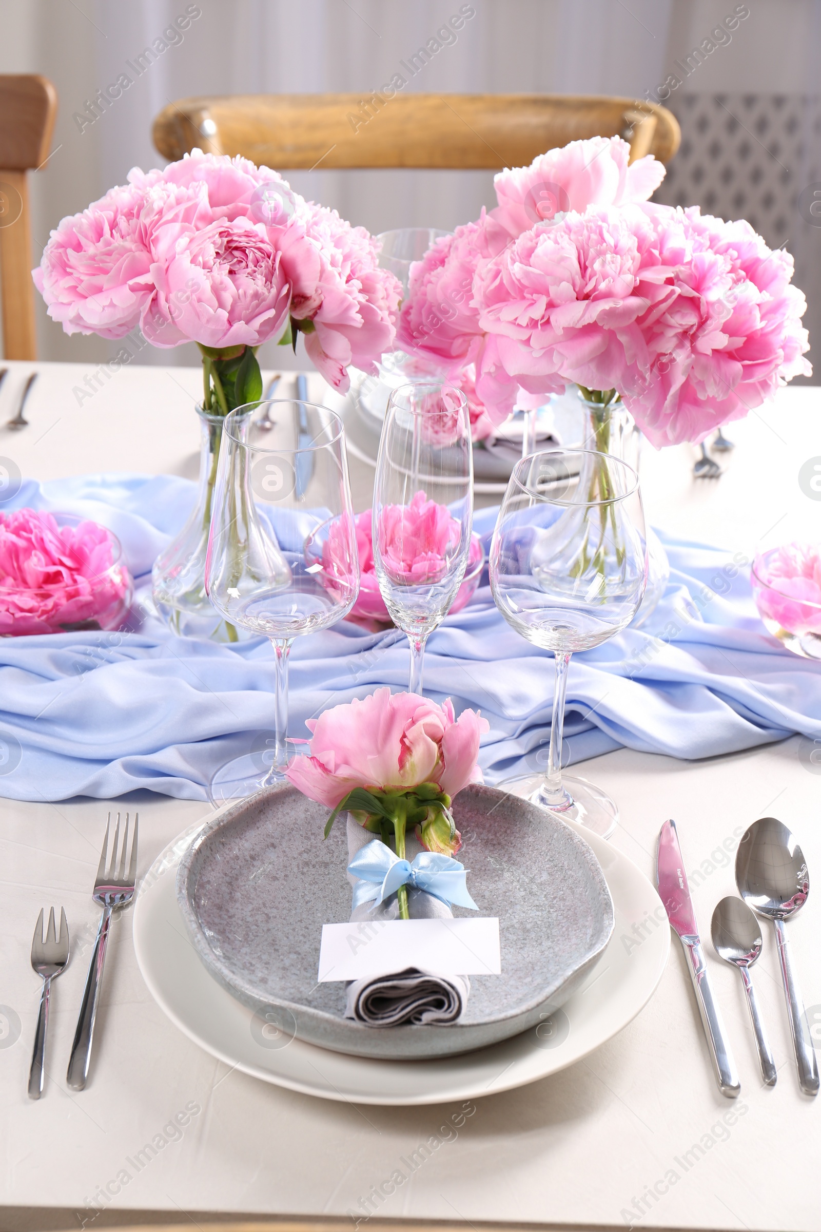 Photo of Stylish table setting with beautiful peonies, napkin and blank card indoors