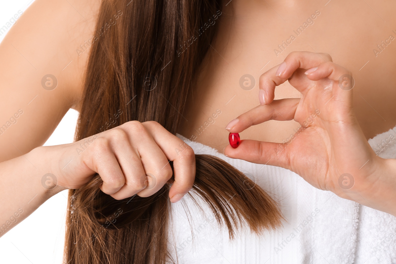Photo of Woman holding vitamin capsule for hair health on white background, closeup