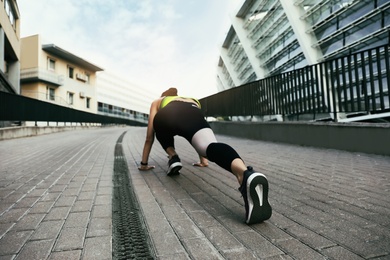 Photo of Young woman stretching after running on street