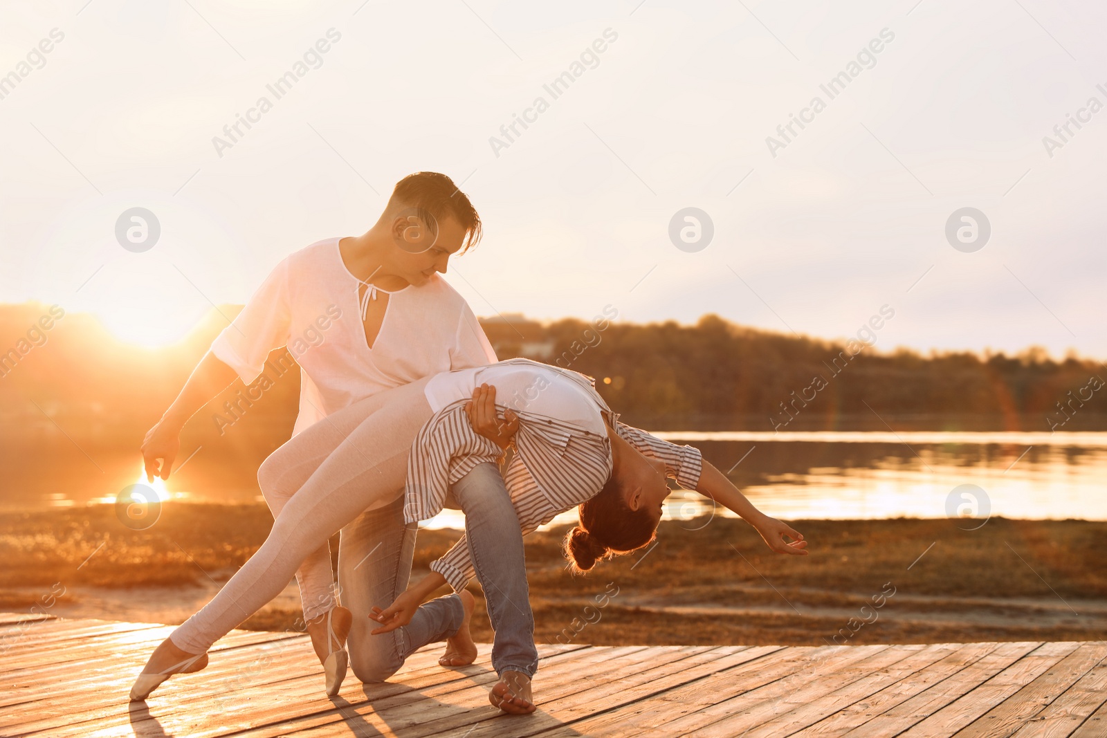 Photo of Beautiful young couple practicing dance moves near river at sunset