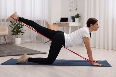 Happy woman doing morning exercise with stretching band at home