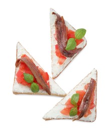 Photo of Delicious sandwiches with cream cheese, anchovies, tomatoes and basil on white background, top view