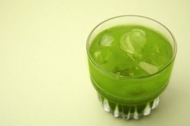 Photo of Glass of delicious iced matcha tea on green background, closeup. Space for text