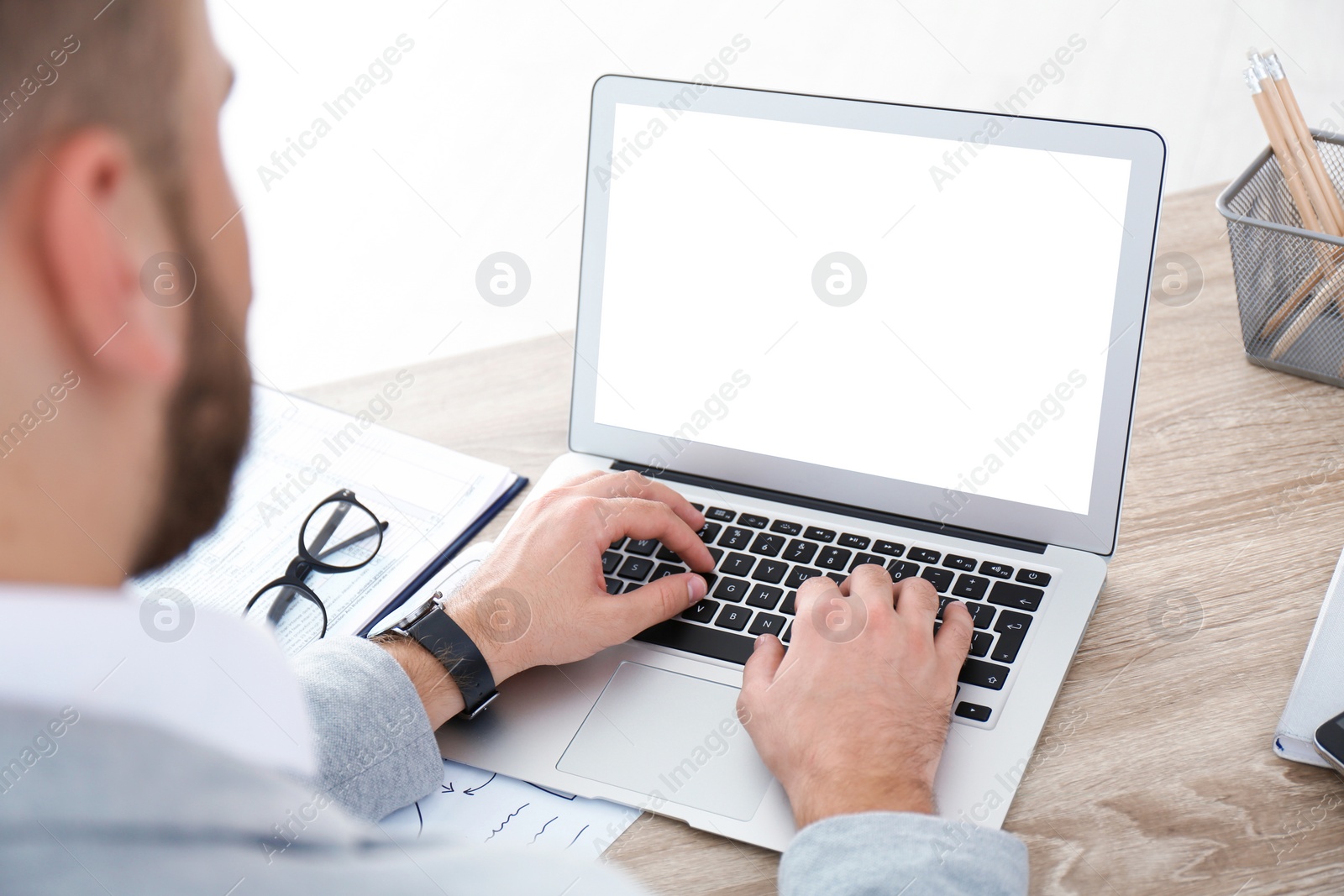 Image of Young man using modern computer at table in office, closeup. Space for design