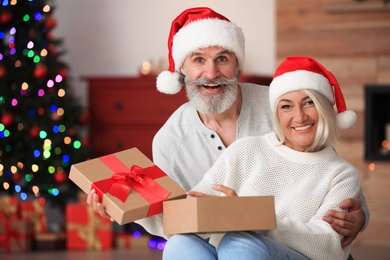 Happy couple opening Christmas gift at home