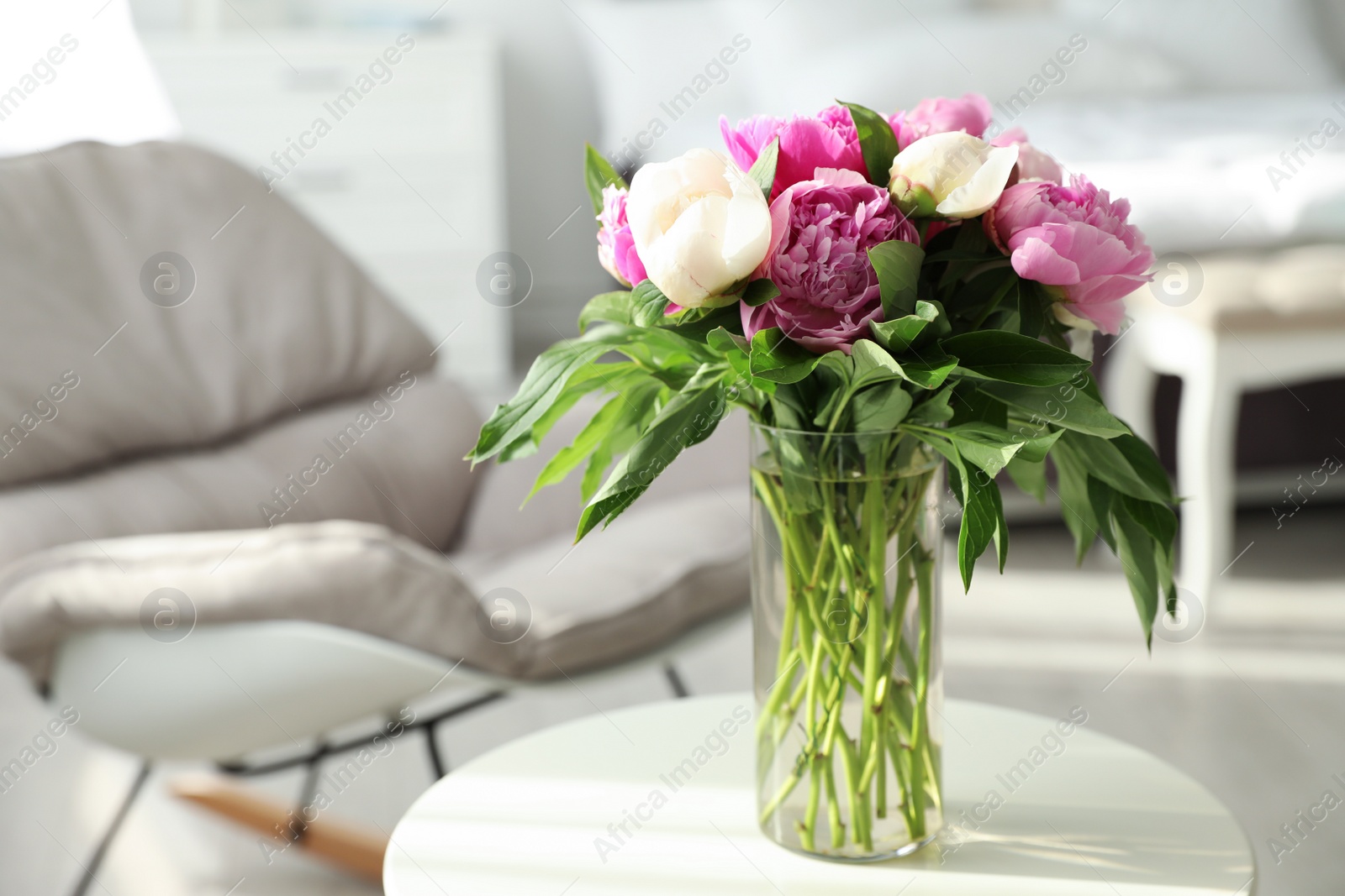 Photo of Vase with bouquet of beautiful peonies on table in room, space for text