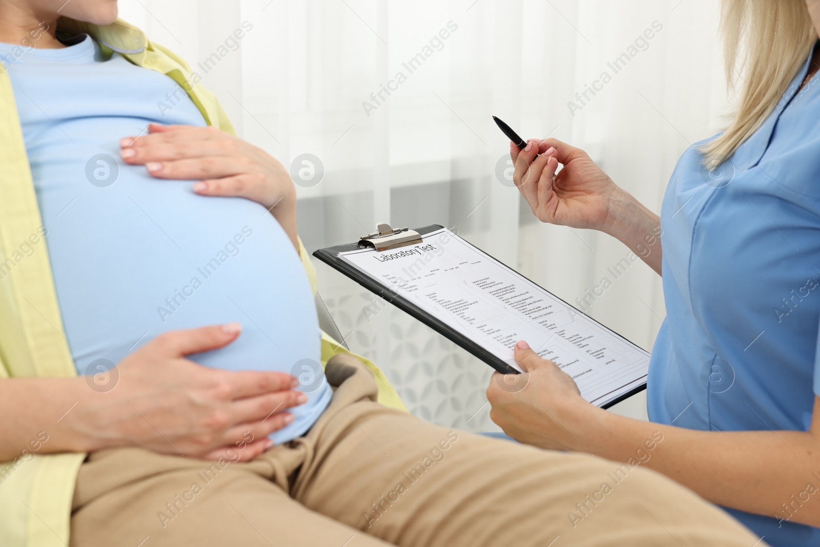 Photo of Doctor with results of laboratory test consulting pregnant patient in clinic, closeup