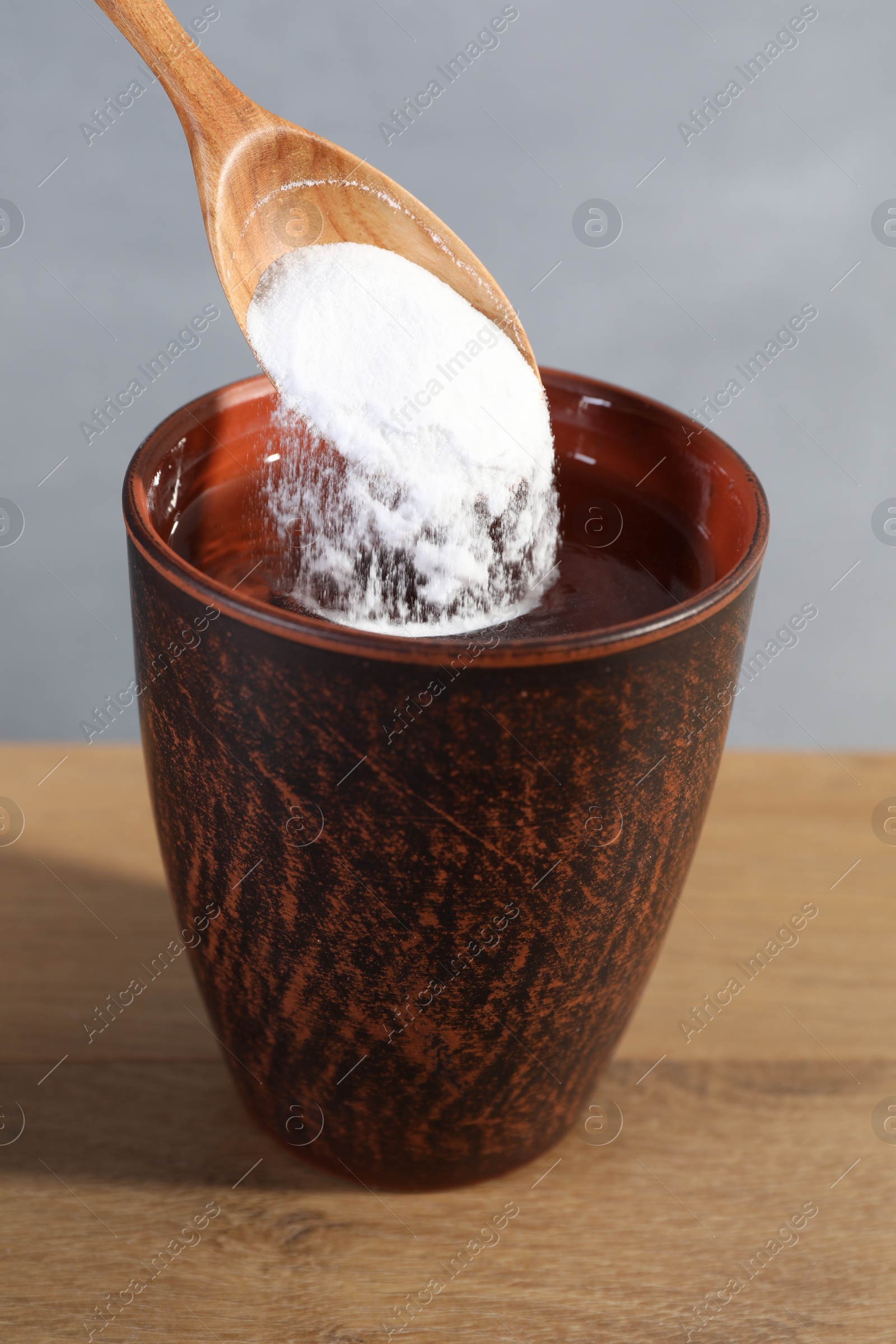 Photo of Adding baking soda into water at wooden table