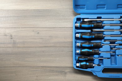 Photo of Set of screwdrivers in open toolbox on wooden table, top view. Space for text