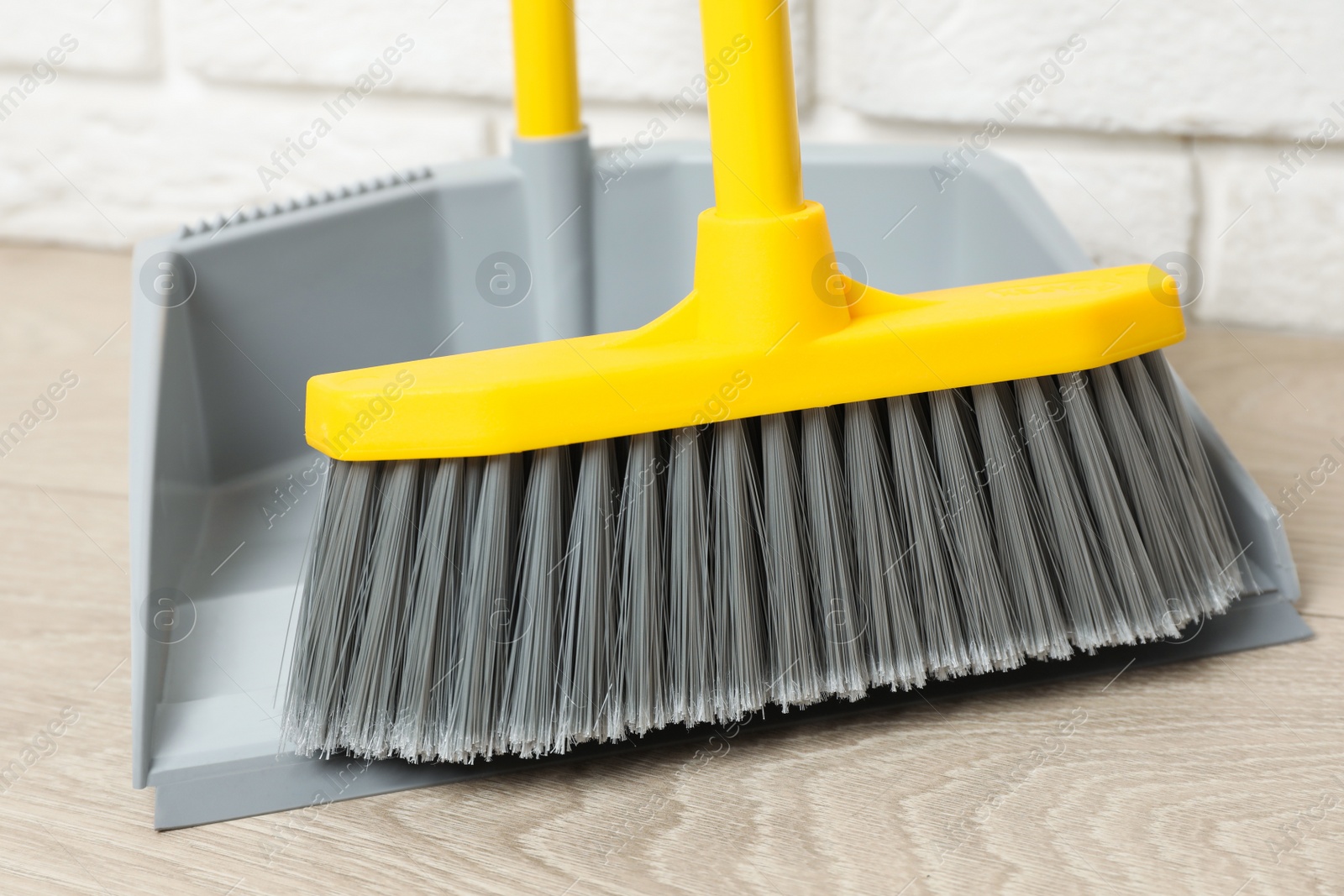 Photo of Plastic broom with dustpan on wooden floor indoors, closeup