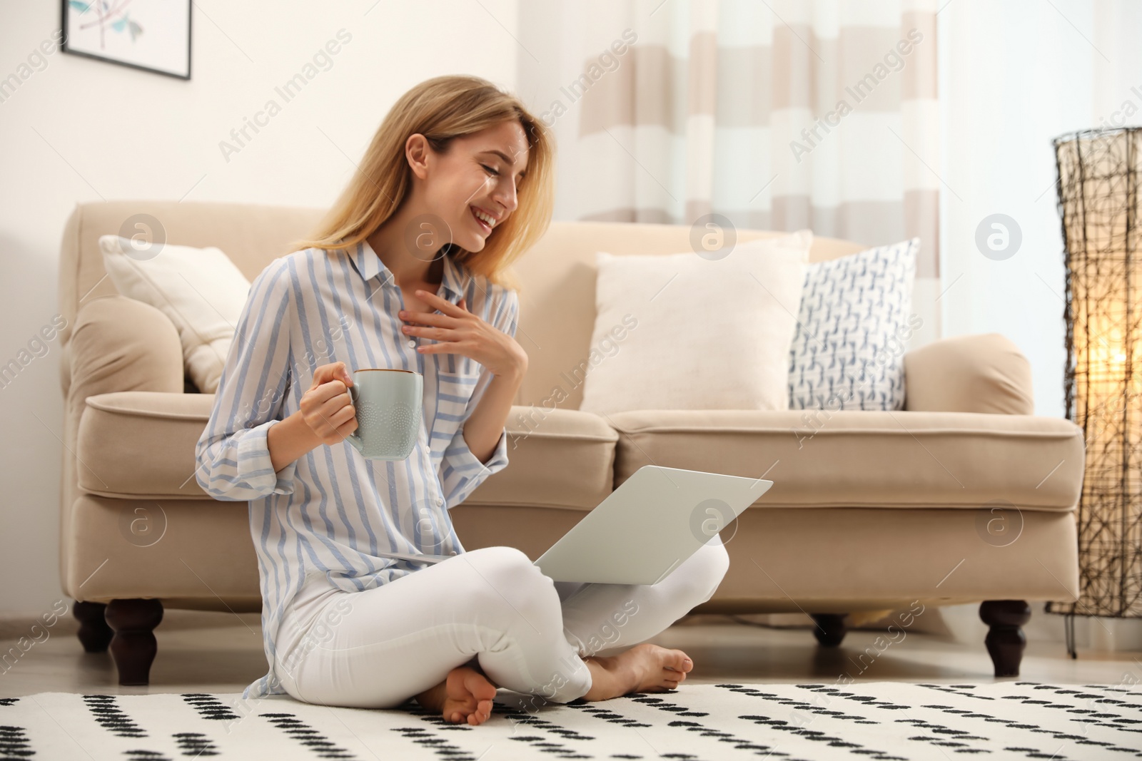 Photo of Pretty young woman with laptop sitting on floor at home