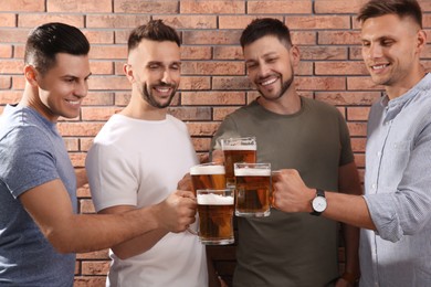 Friends clinking glasses of beer near red brick wall