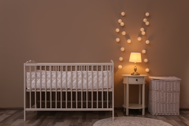Photo of Nursery room interior with comfortable bed and fairy lights