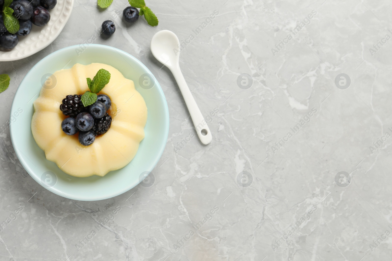 Photo of Delicious semolina pudding with berries on light grey table, flat lay. Space for text