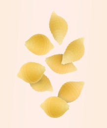 Raw conchiglie pasta flying on beige background