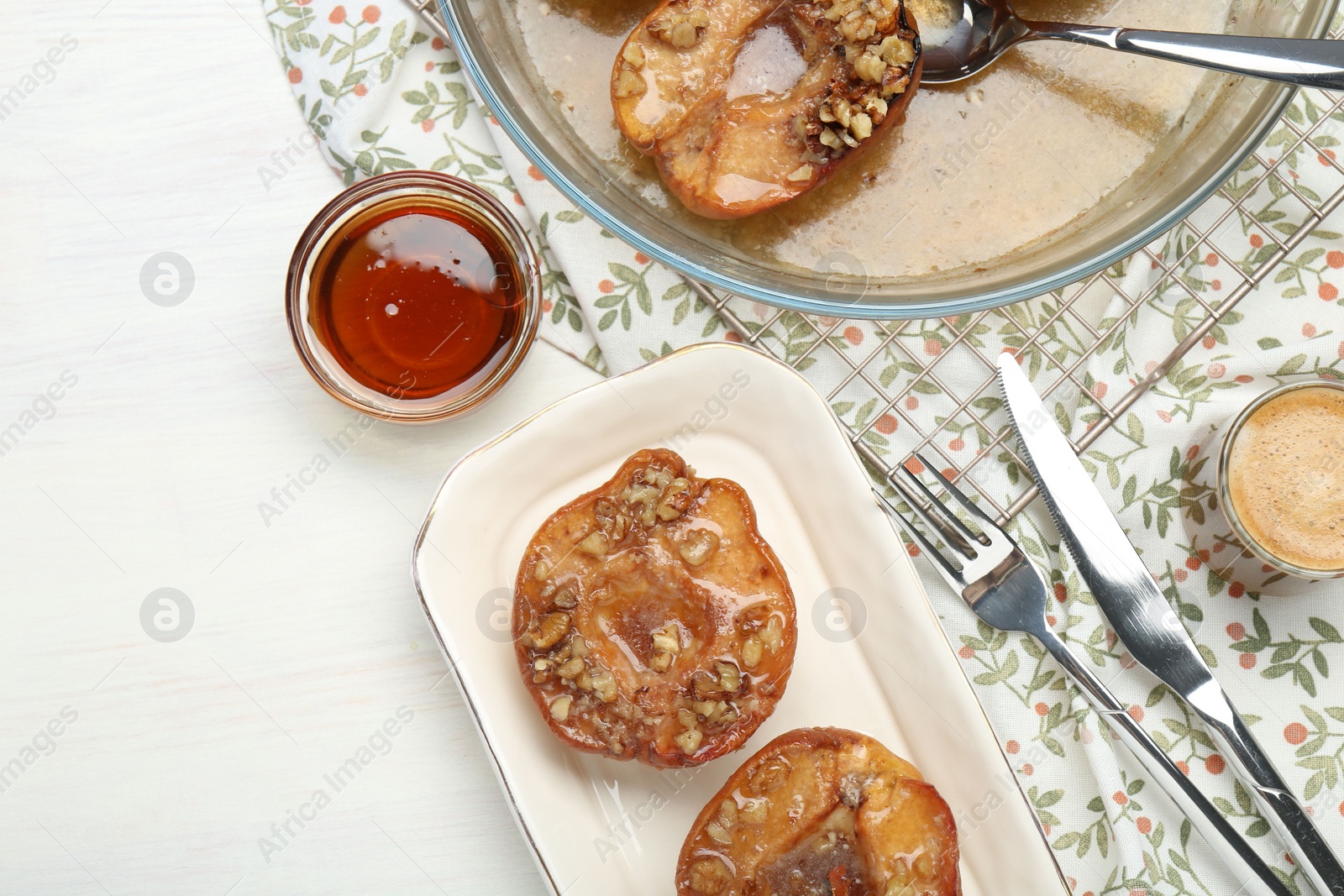 Photo of Delicious quinces baked with honey and walnuts on white wooden table, flat lay