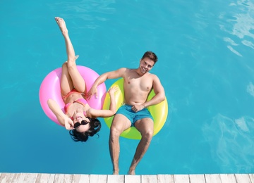 Woman in bikini with boyfriend swimming at resort. Happy young couple