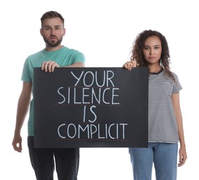 Photo of Young man and African American woman holding sign with phrase Your Silence Is Complicit on white background. Racism concept