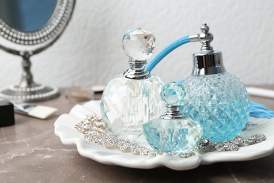 Plate with perfume bottles and jewellery on dressing table