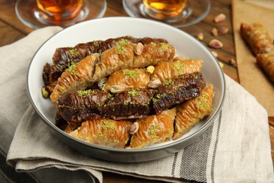 Photo of Delicious sweet baklava with pistachios in bowl on table, closeup