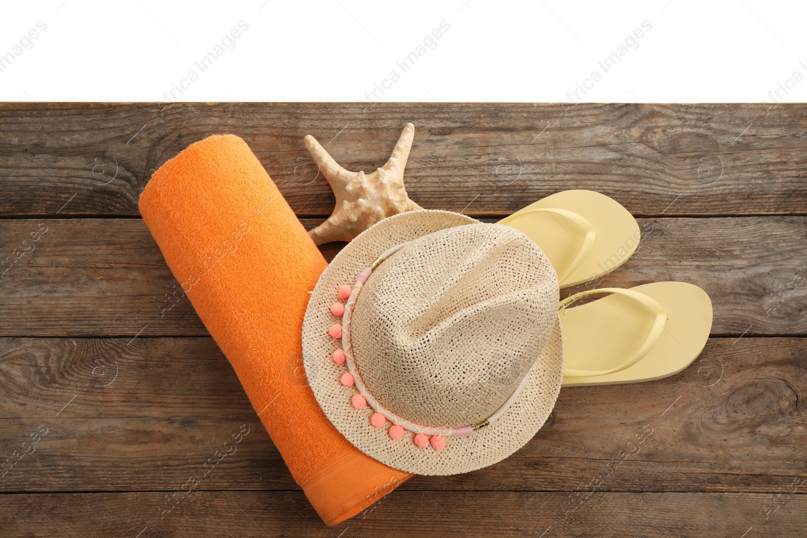 Photo of Wooden surface with beach towel, straw hat and flip flops on white background, top view
