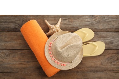 Photo of Wooden surface with beach towel, straw hat and flip flops on white background, top view