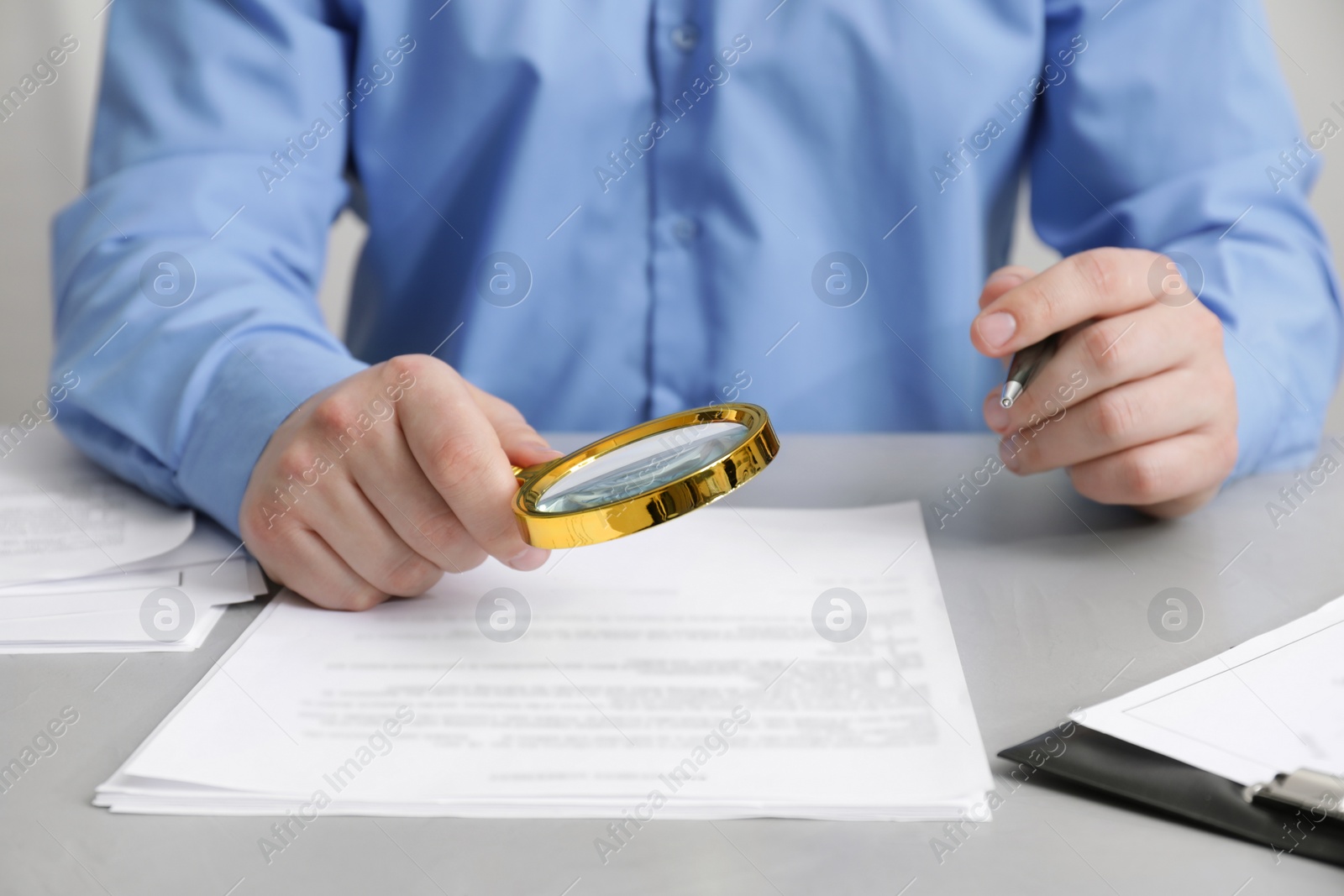 Photo of Man looking at document through magnifier at white table, closeup. Searching concept