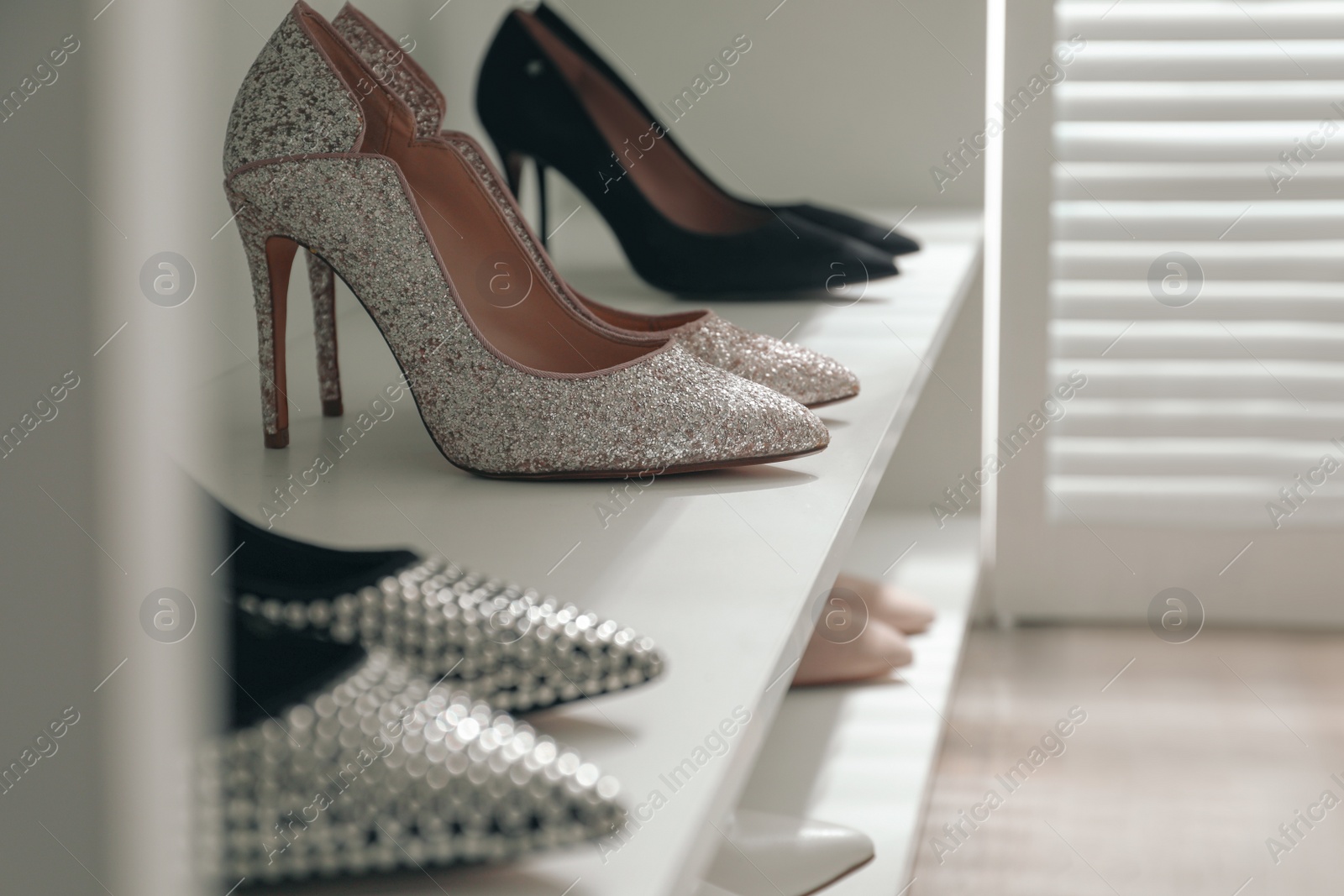 Photo of Storage rack with stylish women's shoes indoors, closeup