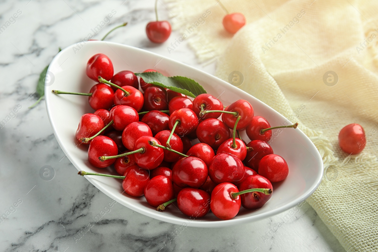 Photo of Bowl with sweet red cherries on marble table