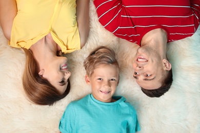 Little boy with mother and father lying on fuzzy rug, top view