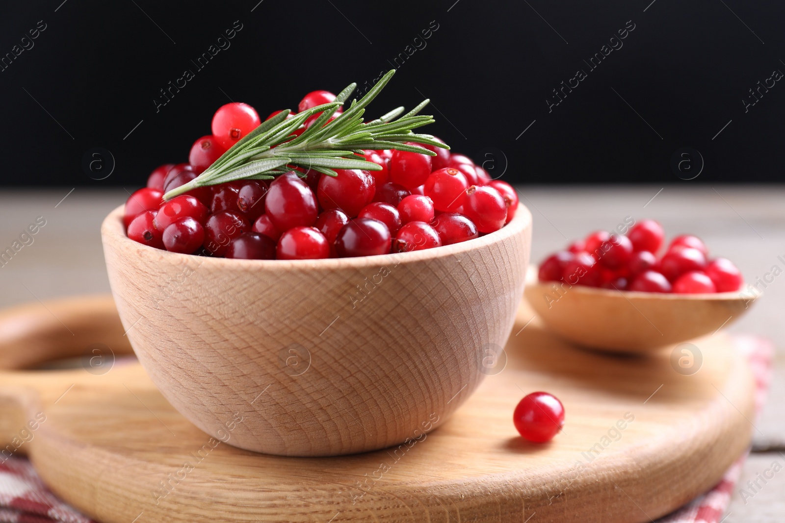 Photo of Fresh ripe cranberries and rosemary on wooden table, closeup