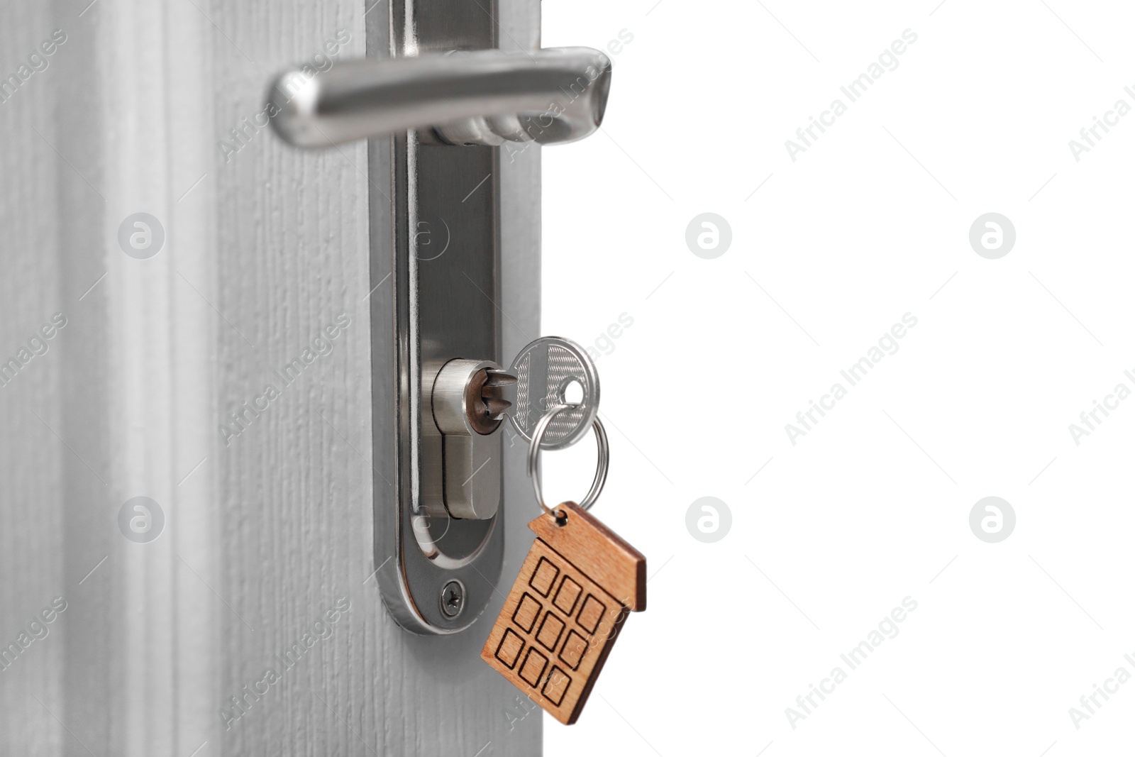 Photo of Open door with key on blurred background, closeup. Space for text