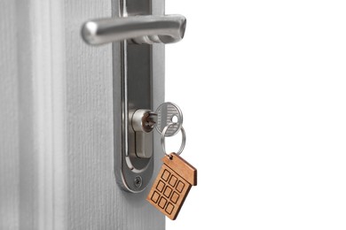 Open door with key on blurred background, closeup. Space for text