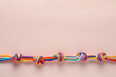 Colorful ropes tied together with many knots on light background, top view. Unity concept