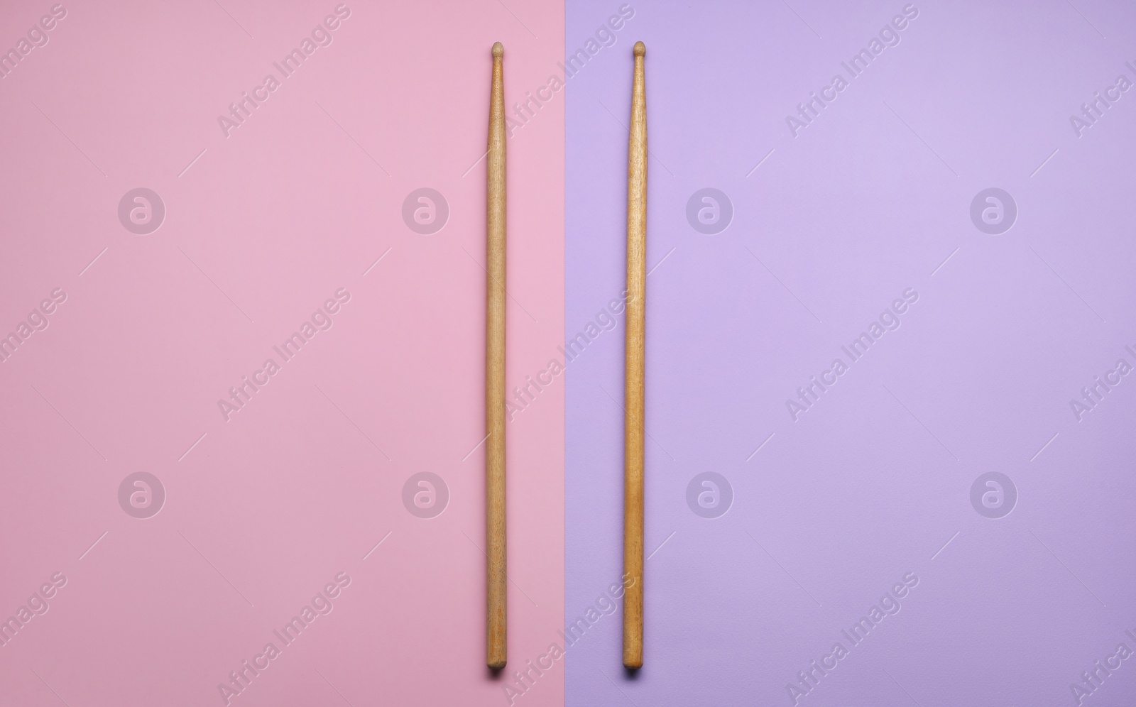 Photo of Two wooden drum sticks on color background, top view