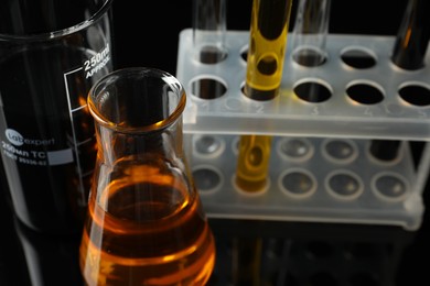 Photo of Laboratory glassware with different types of oil on black background, closeup