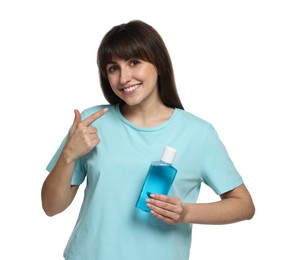 Photo of Young woman with mouthwash pointing at her healthy teeth on white background