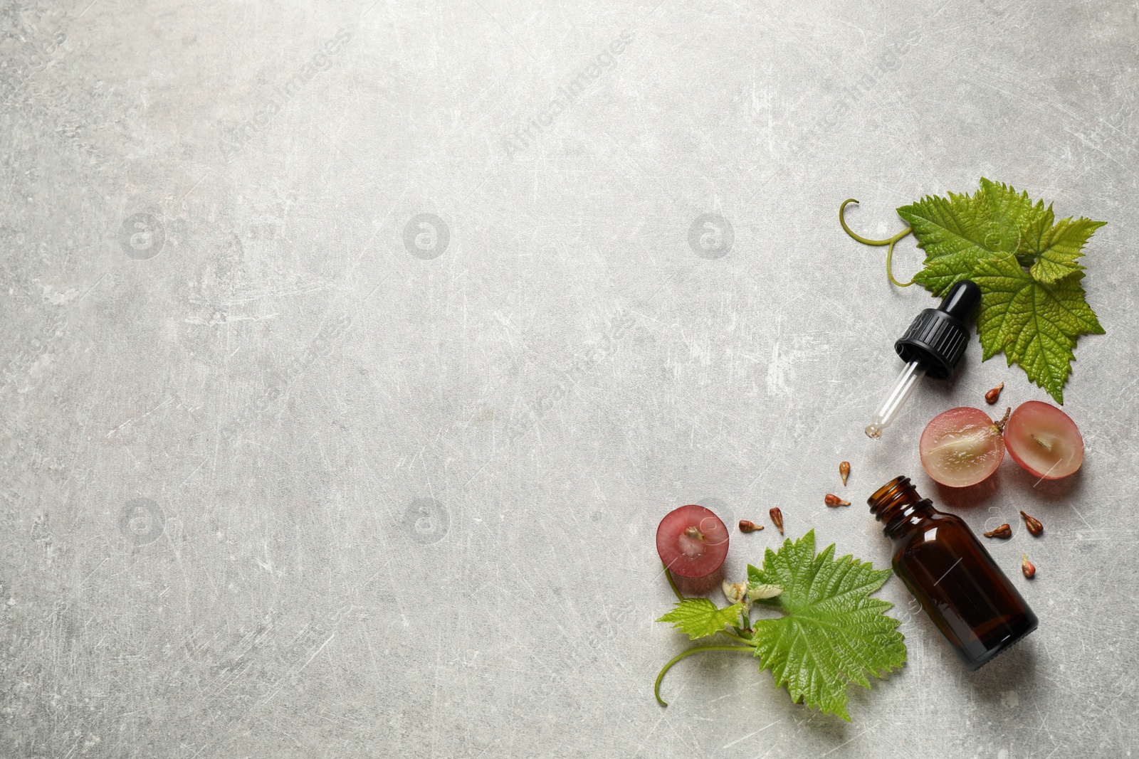 Photo of Bottle of natural grape seed oil on light table, flat lay with space for text. Organic cosmetic