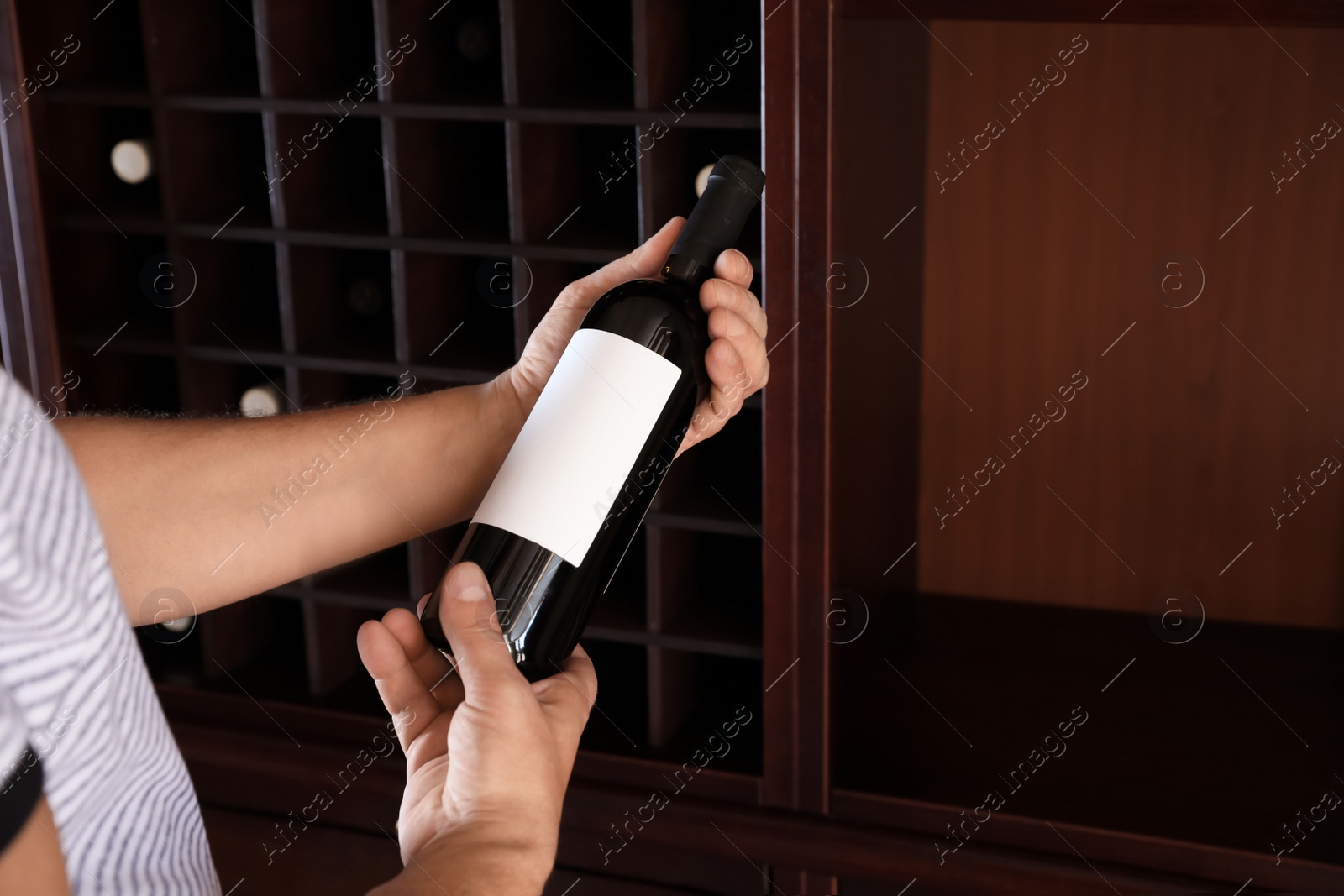 Photo of Man with bottle of expensive wine indoors, closeup