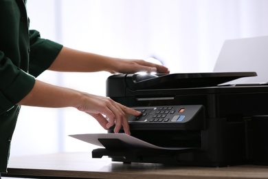 Photo of Employee using modern printer in office, closeup