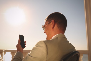 Photo of Businessman talking on smartphone in outdoor cafe