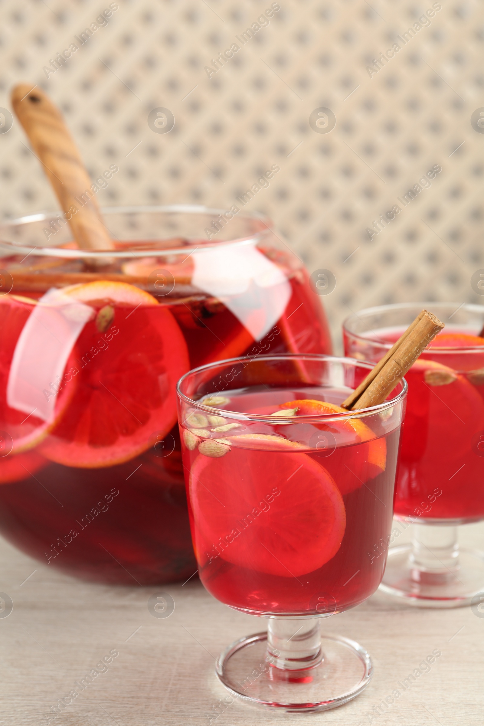 Photo of Glasses and bowl with aromatic punch drink on white wooden table