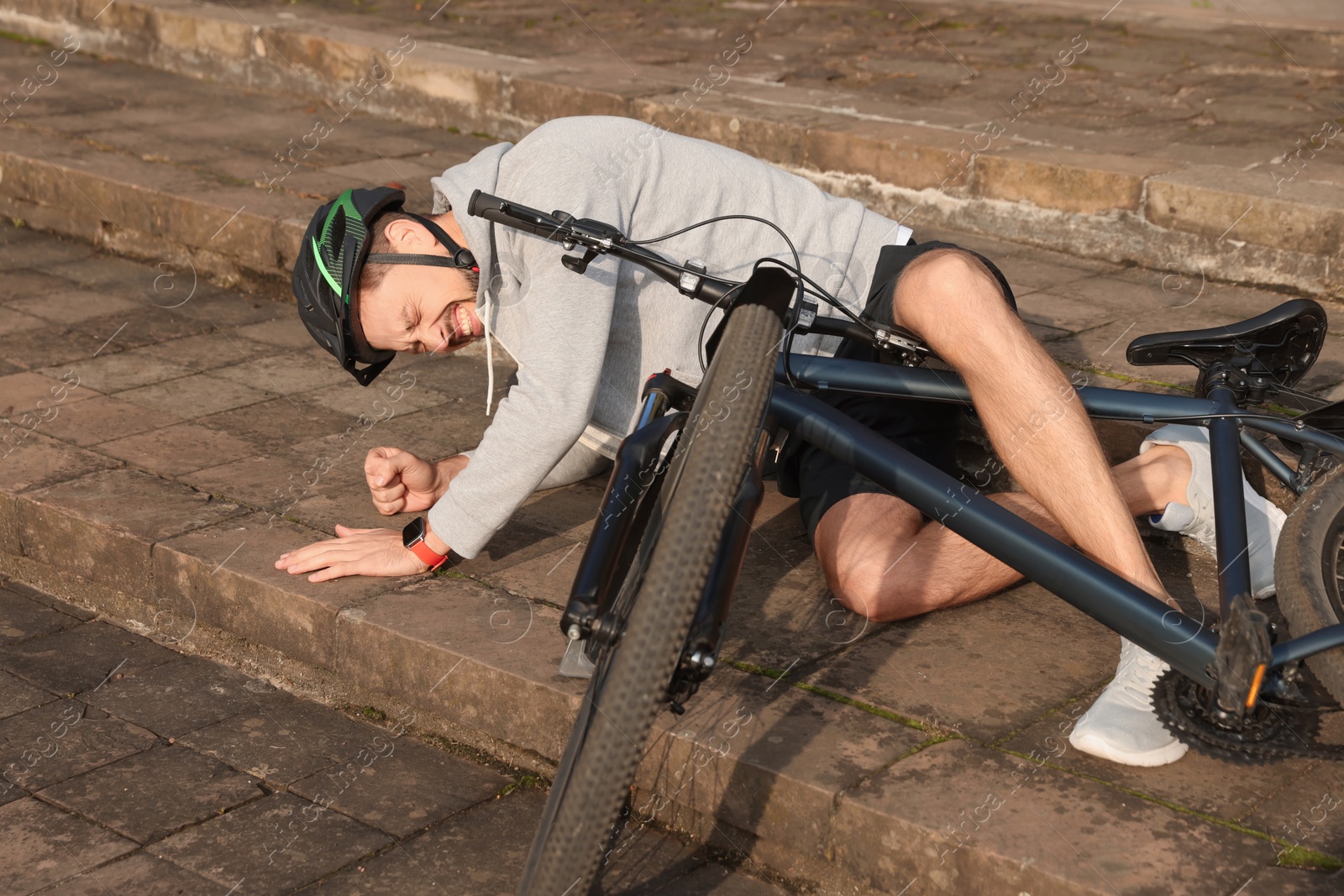 Photo of Man fallen off his bicycle on steps outdoors