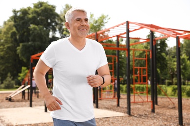 Photo of Handsome mature man running on sports ground, space for text. Healthy lifestyle