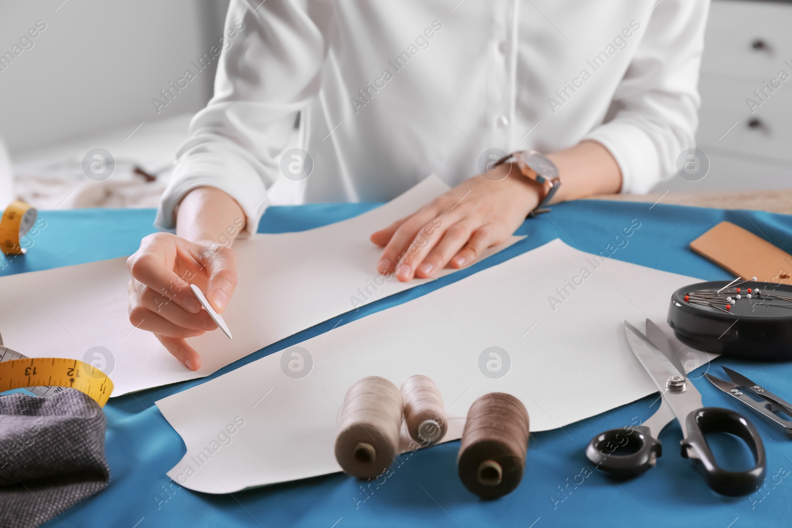 Photo of Tailor working at table in atelier, closeup