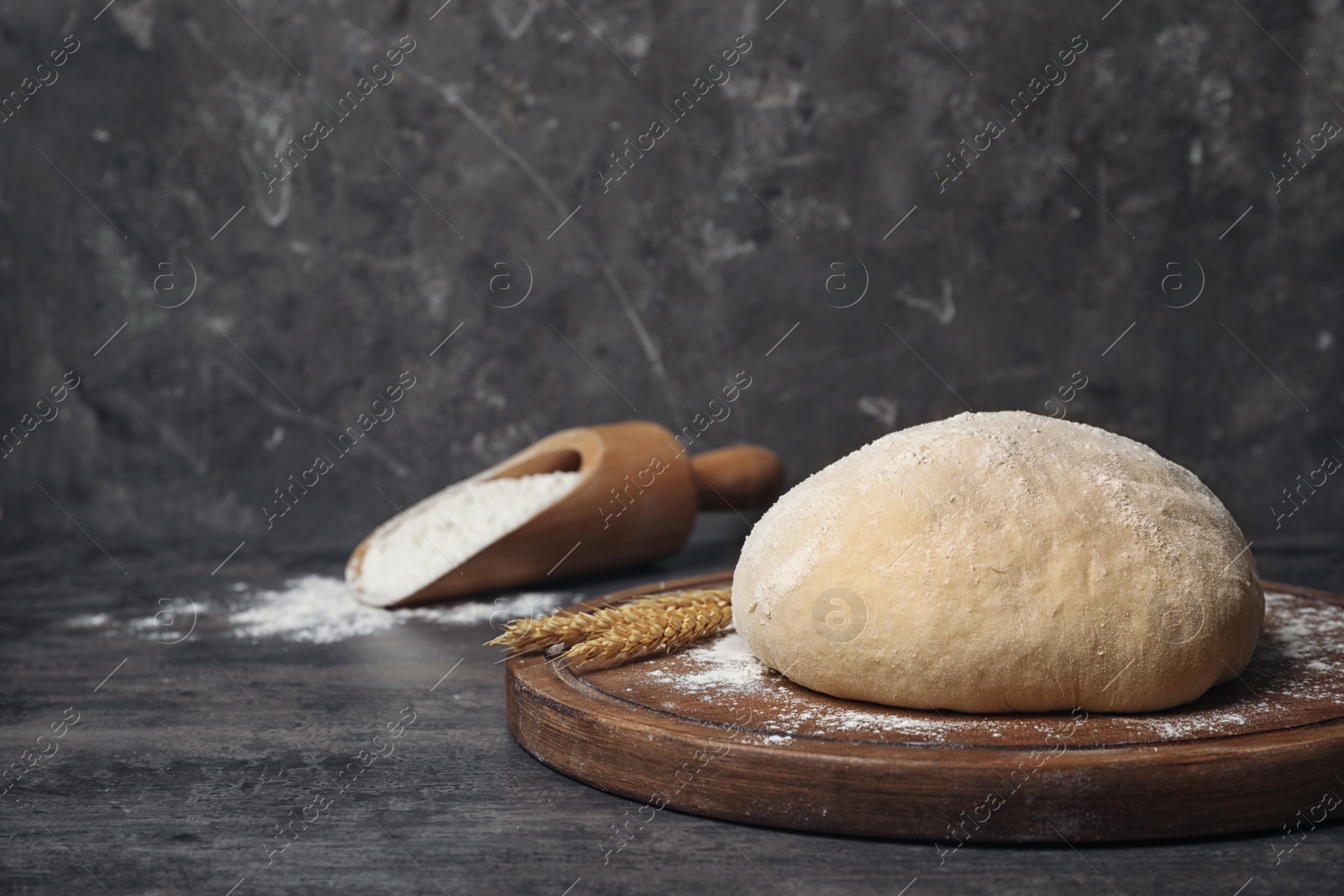 Photo of Wooden board with raw wheat dough on table